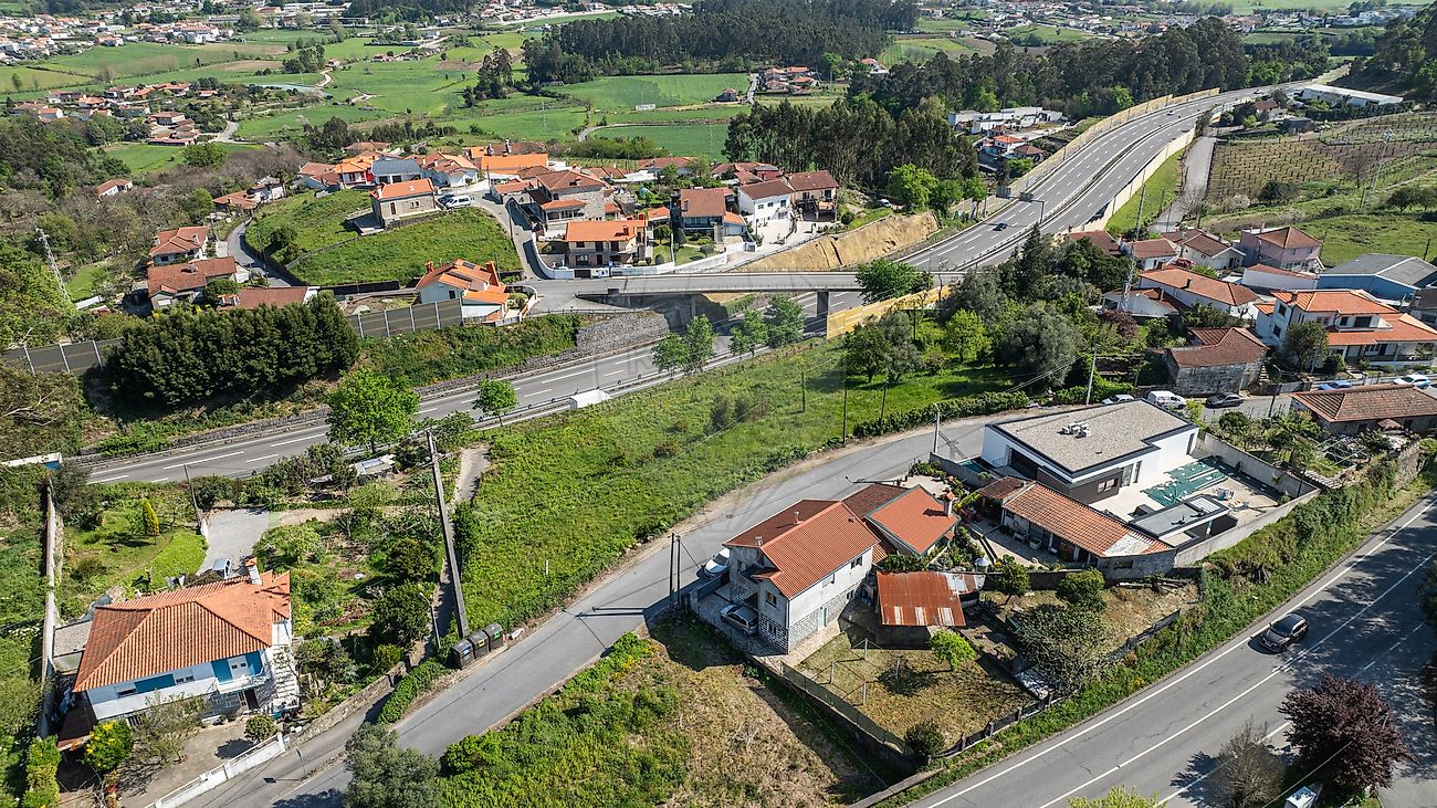 Perspetiva aérea lateral panorâmica evidenciando a envolvência, habitações circundantes e a malha urbana do lote