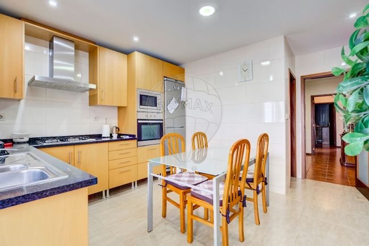 Cozinha espaçosa com mesa de refeições em vidro e armários em madeira