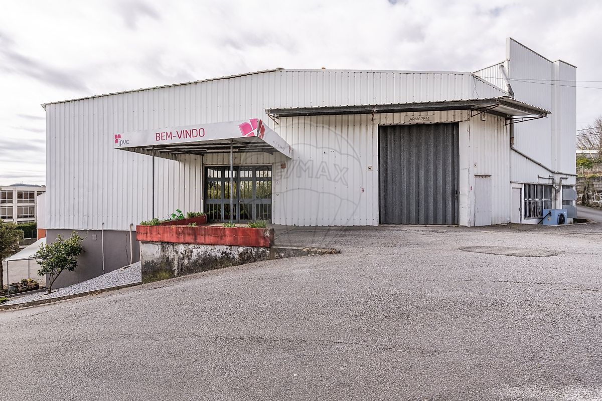 Fachada principal do armazém industrial para venda em Vila Nova de Famalicão com cais de carga e portão de fole