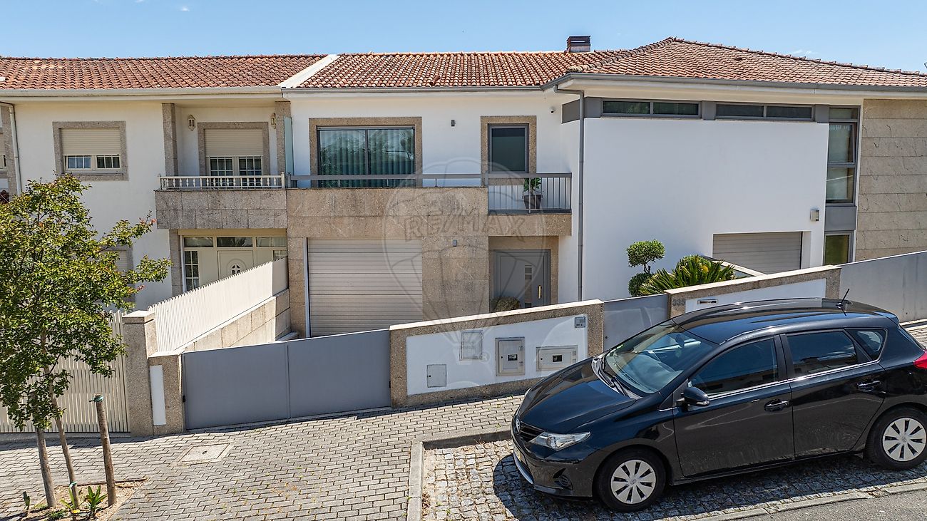 Fachada principal de moradia de luxo em Guimarães com acabamentos em pedra natural e garagem fechada
