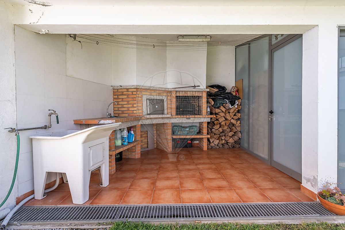 Zona de churrasqueira exterior coberta com forno a lenha tradicional para convívios familiares