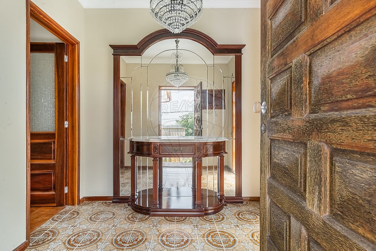 Hall de entrada com chão decorado e móvel com espelho em moradia de Famalicão