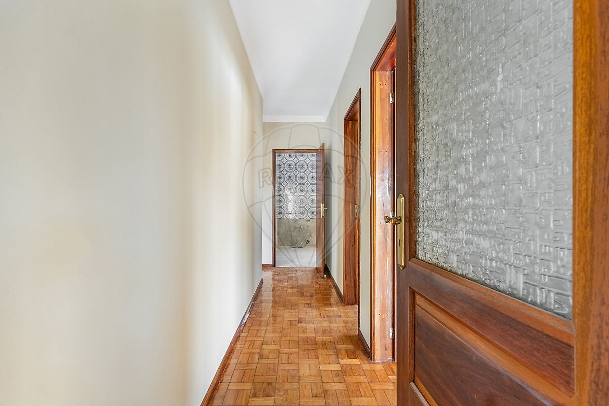 Amplo hall de circulação interior com portas de madeira e acesso às divisões