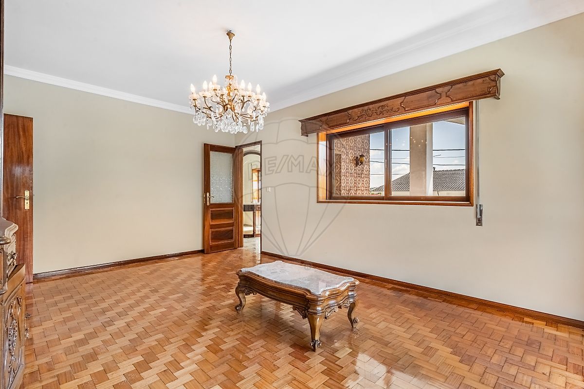 Sala de estar ampla com piso em taco de madeira e lustre clássico