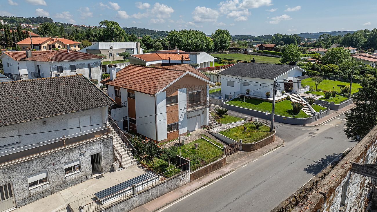 Vista exterior lateral da casa com garagem e arruamento envolvente em Famalicão
