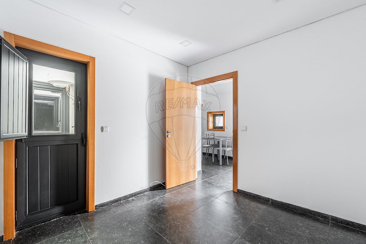 Sala de estar da moradia T1 remodelada com piso escuro e excelente iluminação